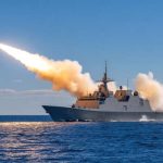 Warship launches missile on open ocean, projecting defense and military might